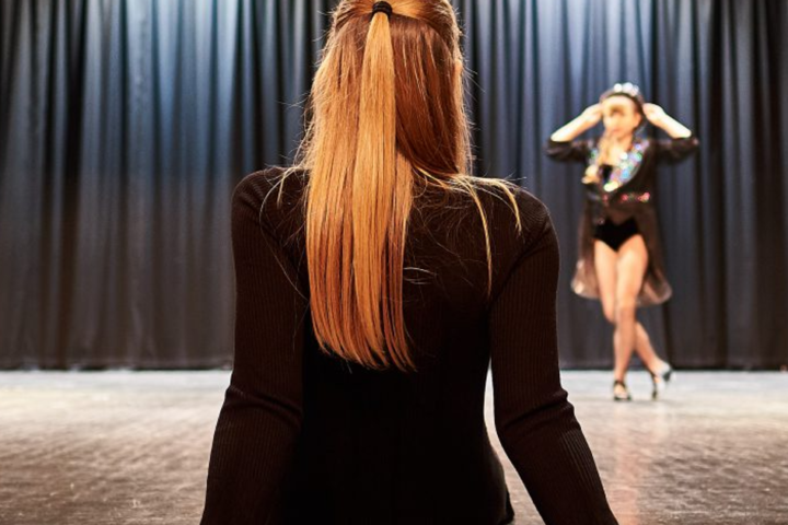 girl with long hair watches dancer on stage